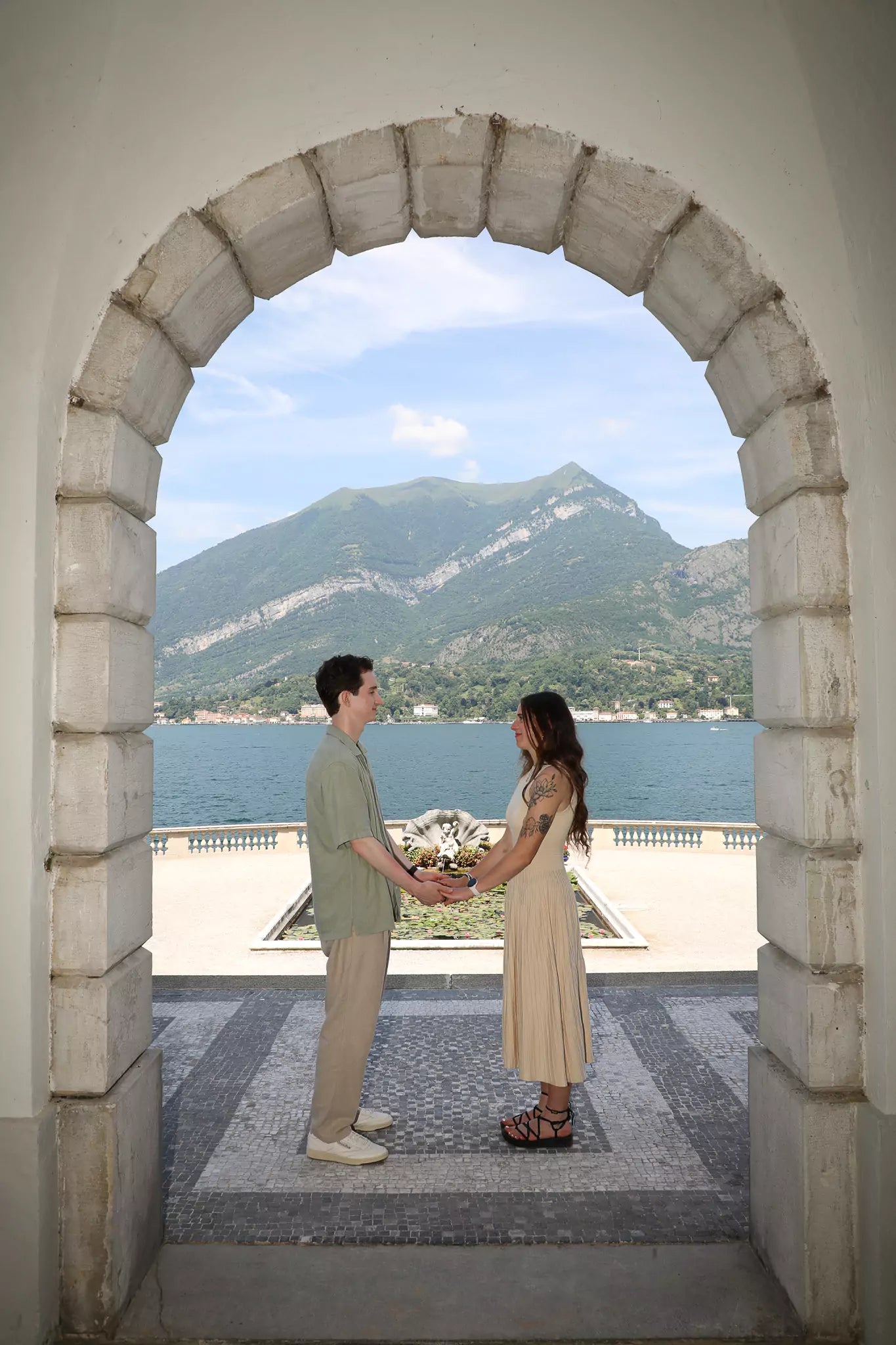 Romantic couple holding hands and gazing at each other after a proposal at Villa Melzi Gardens in Bellagio, Lake Como