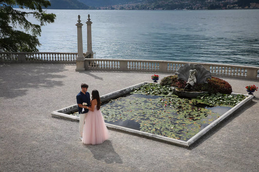 Elegant Lake Como engagement outfits in soft neutrals with movement-friendly fabrics on a waterfront promenade at golden hour — by Nadia Fraqair