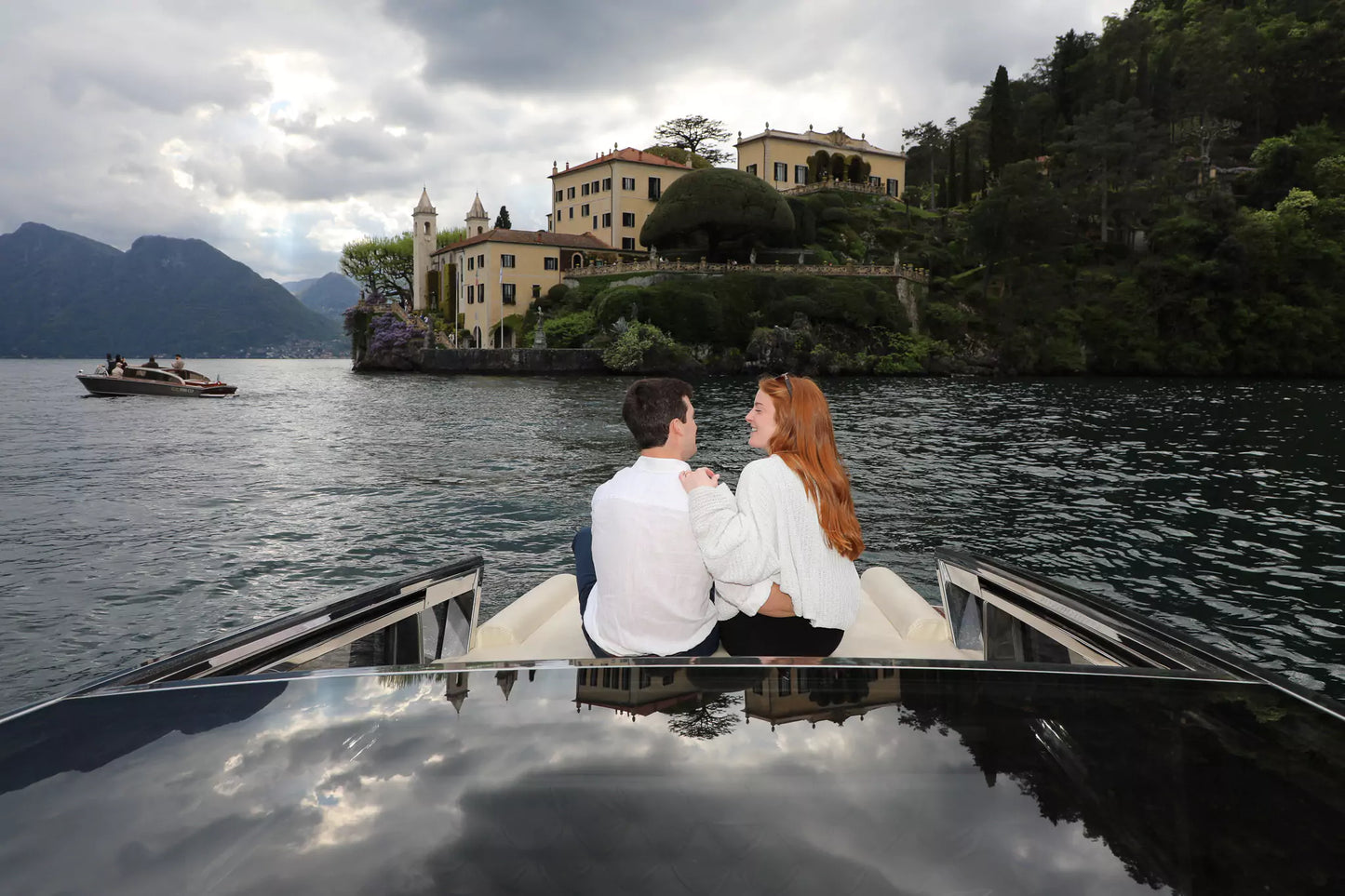 Just-engaged couple cuddling on boat after proposal in Lake Como
