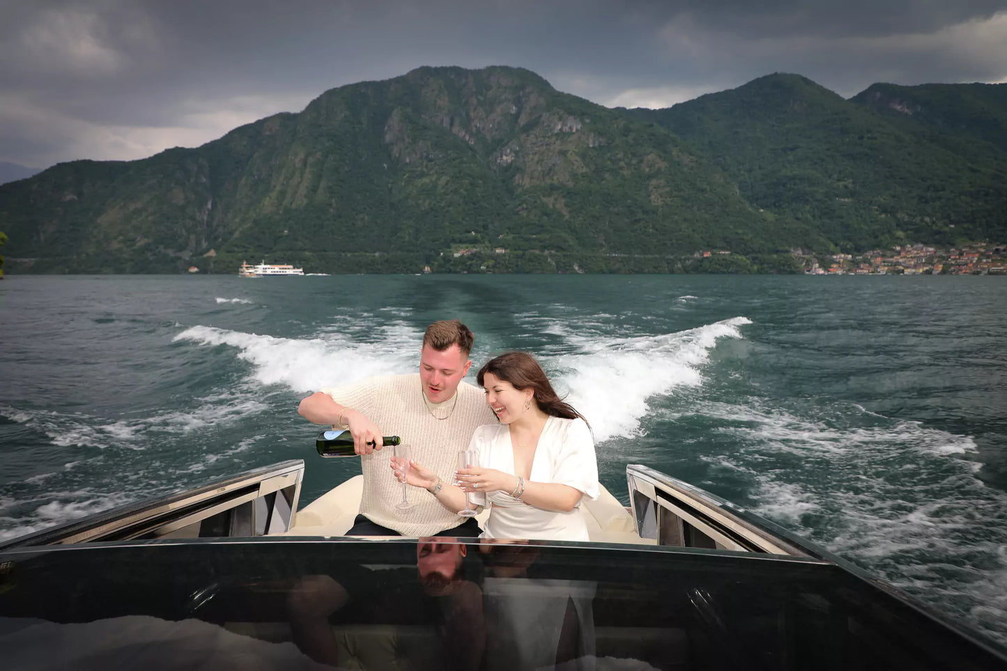 Couple celebrating engagement on Lake Como private boat with champagne